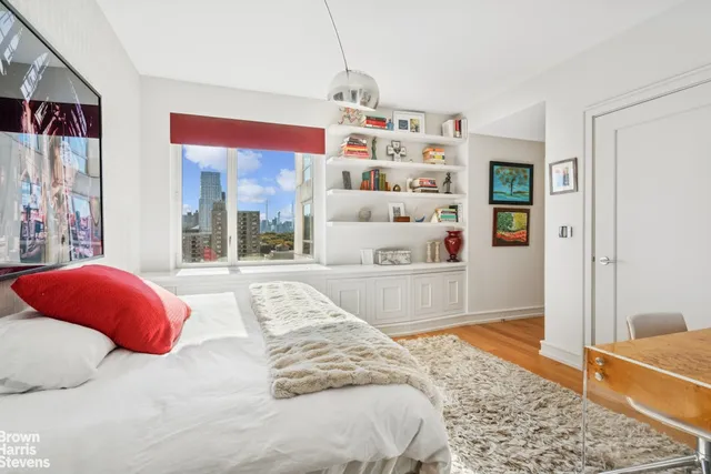 a bedroom with a bed and a large window with the outer view