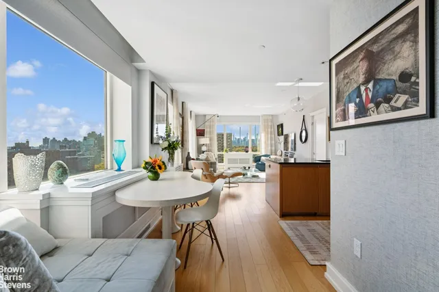 a living room with furniture a large window and dining table