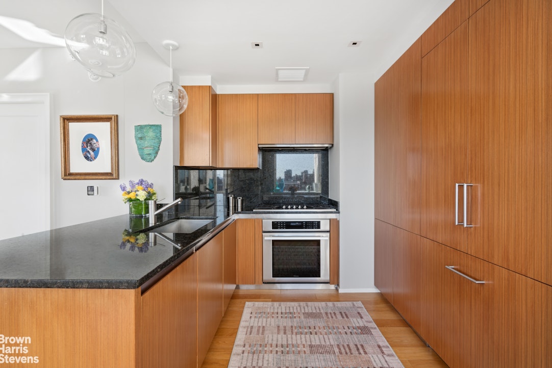 1280 5th Avenue, Unit 19C Manhattan, NY 10029 - Photo 5 of 20 a kitchen with granite countertop cabinets stainless steel appliances and a counter top space