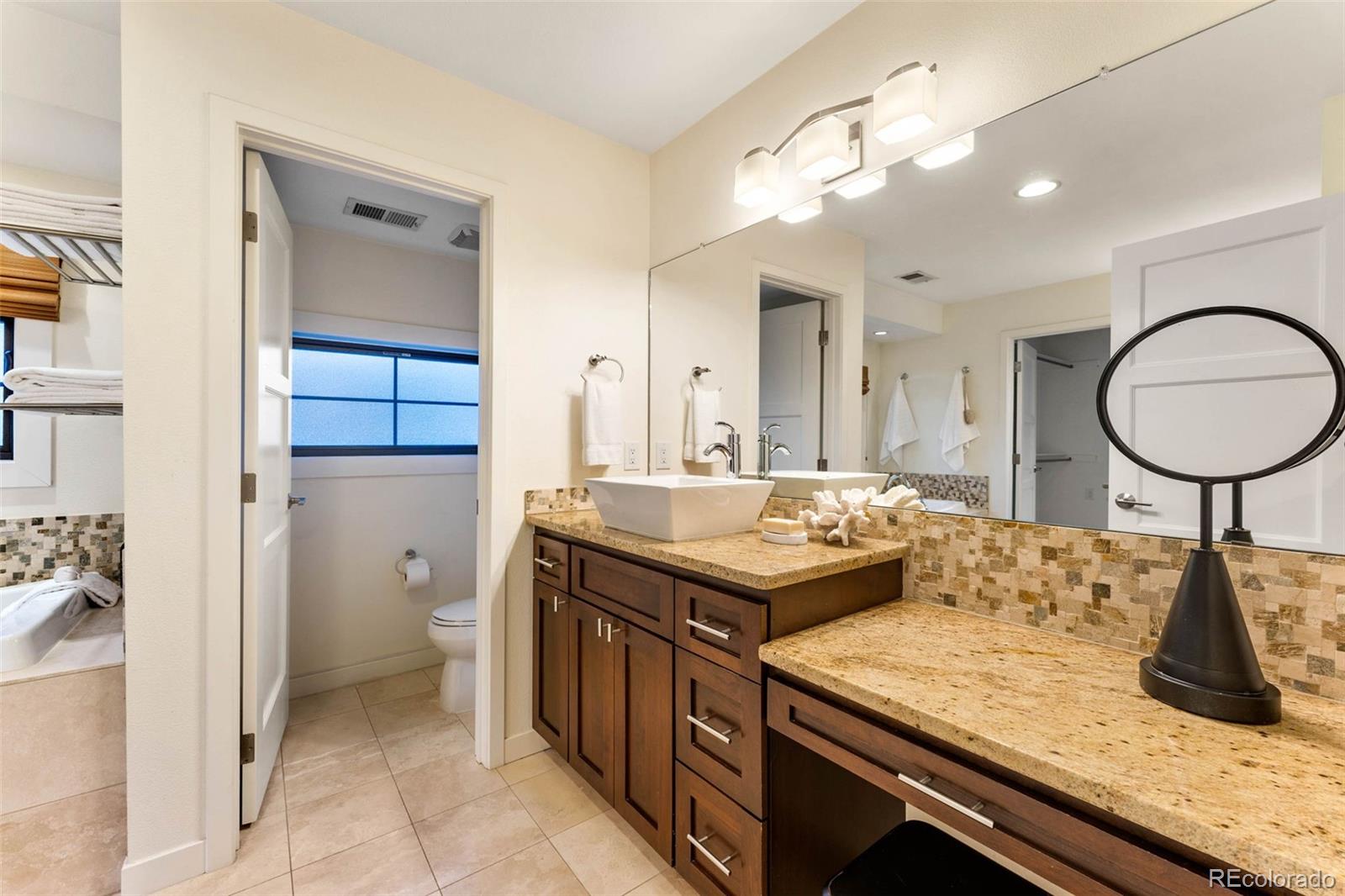 422 Cook Street Denver, CO 80206 - Photo 22 of 40 a bathroom with a granite countertop sink a toilet and a mirror