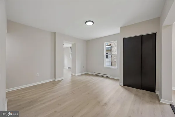 a view of an empty room with closet and wooden floor