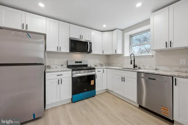 a kitchen with granite countertop a refrigerator stove top oven and sink