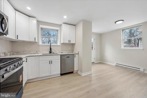 a kitchen with granite countertop a sink cabinets stainless steel appliances and a window