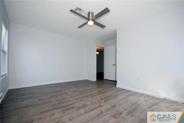 an empty room with wooden floor and ceiling fan