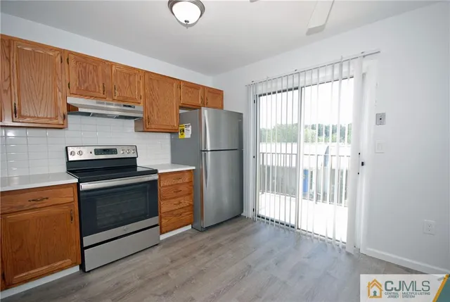 a kitchen with a refrigerator stove and wooden cabinets