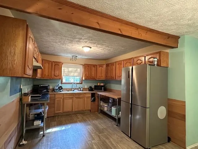 a kitchen with stainless steel appliances granite countertop a refrigerator a sink dishwasher a stove and a microwave oven on granite countertops