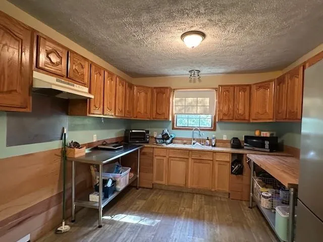 a kitchen with stainless steel appliances granite countertop wooden cabinets a sink dishwasher a stove and a refrigerator