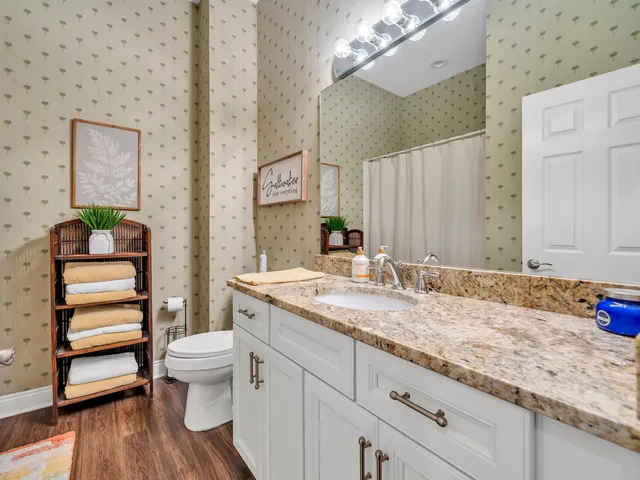 a bathroom with a granite countertop sink and a toilet