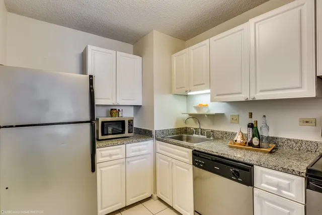 a kitchen with refrigerator a stove a sink and white cabinets