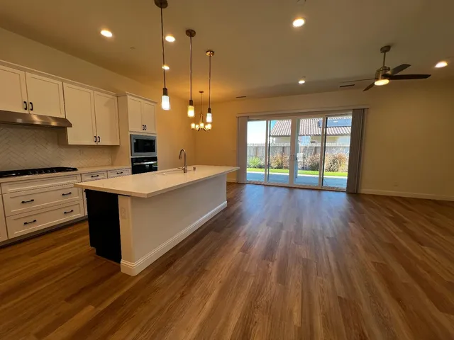 a large kitchen with stainless steel appliances a large counter top a sink a refrigerator and a stove