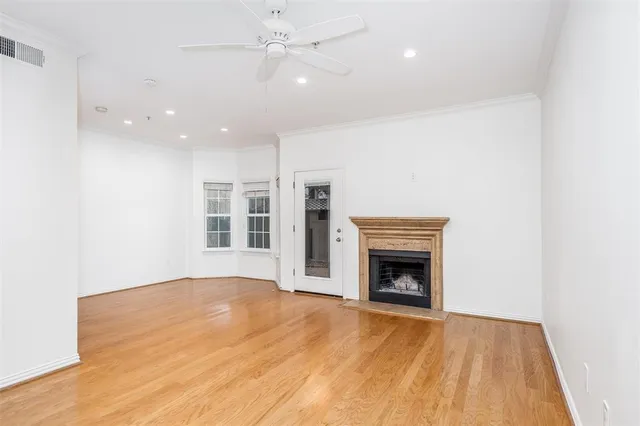 a view of an empty room with wooden floor fireplace and a window