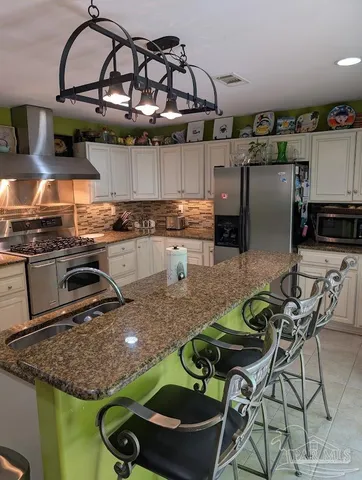 a kitchen with stainless steel appliances granite countertop a sink a stove and a wooden cabinets