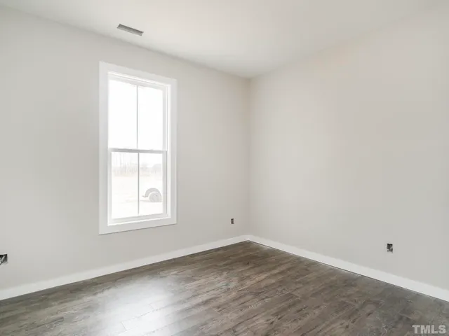 an empty room with wooden floor and window