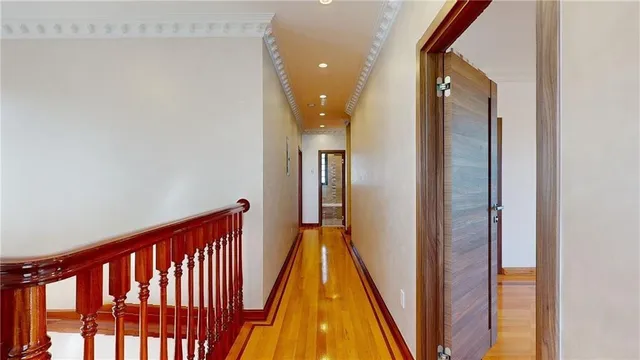 a view of a hallway with wooden floor and a bathroom
