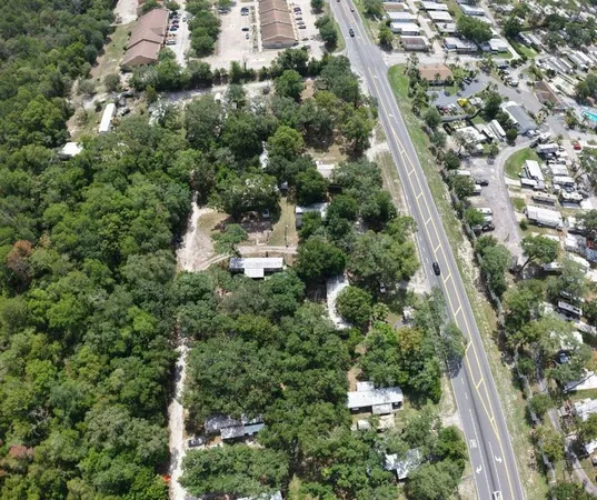 an aerial view of residential houses with outdoor space and trees