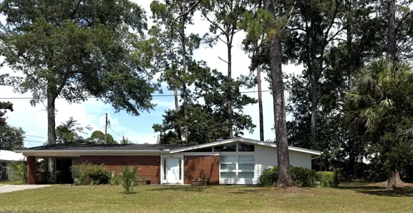 a front view of house with yard and trees in the background