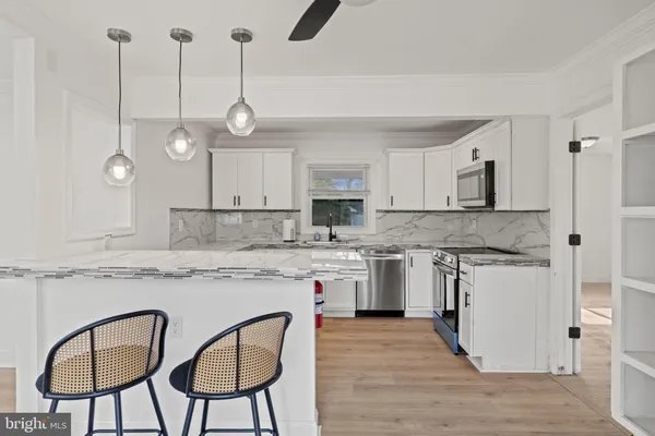 a kitchen with stainless steel appliances granite countertop a stove a sink refrigerator and white cabinets with wooden floor