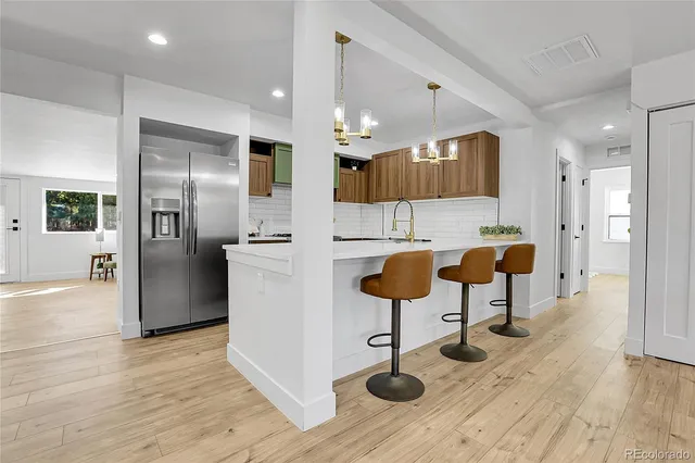 a kitchen with stainless steel appliances kitchen island a refrigerator and a wooden cabinets
