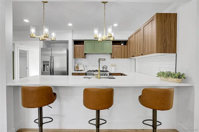 a kitchen with stainless steel appliances granite countertop a sink a stove a refrigerator and cabinets