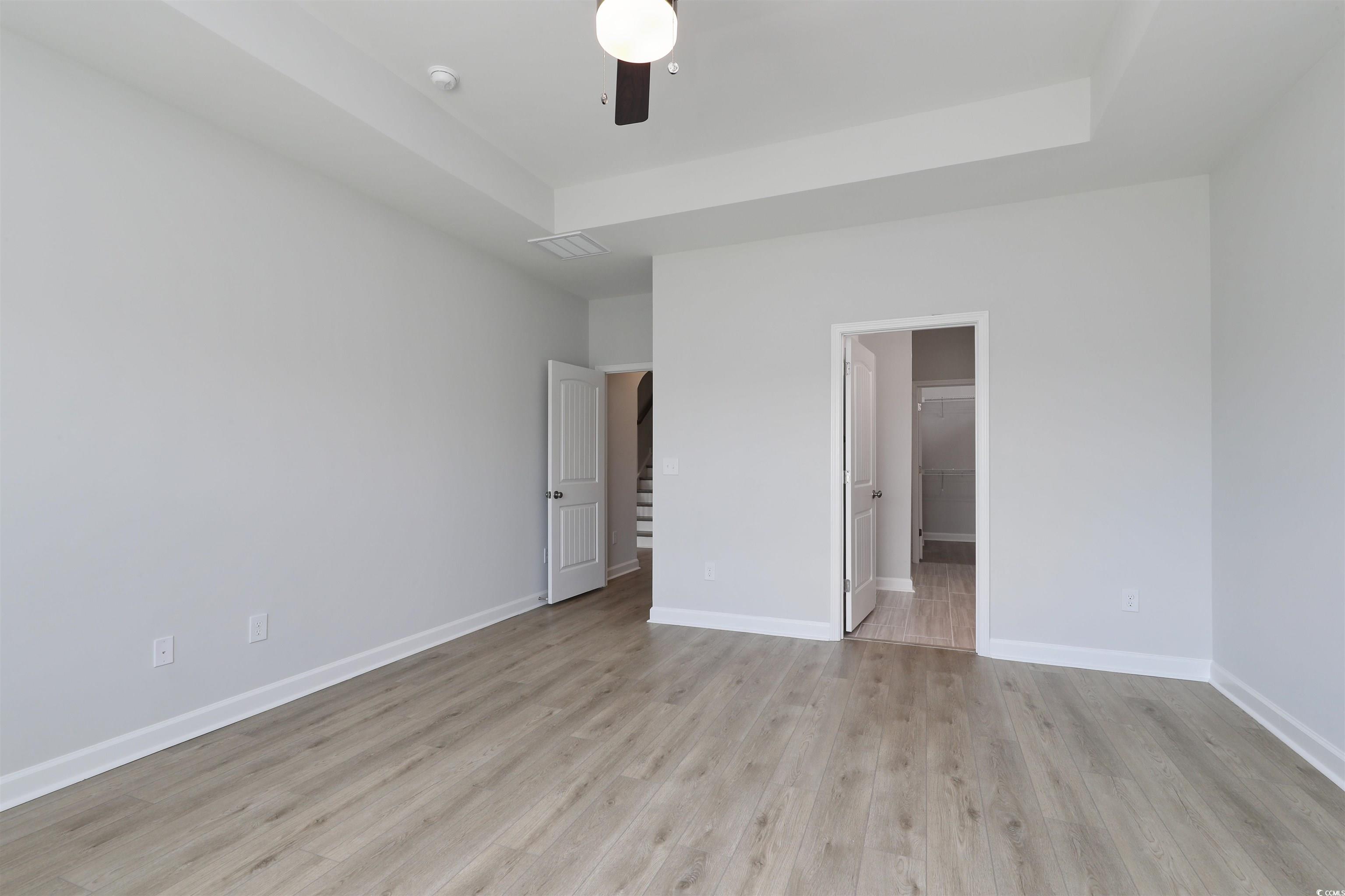 1083 Laconic Drive Myrtle Beach, SC 29588 - Photo 19 of 40 Unfurnished bedroom featuring light wood-style flooring, a raised ceiling, and a ceiling fan
