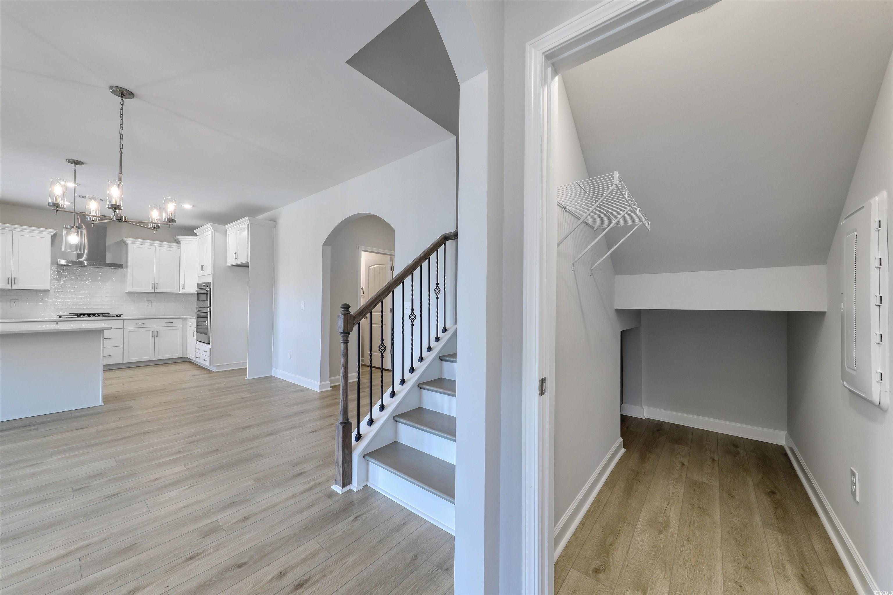 1083 Laconic Drive Myrtle Beach, SC 29588 - Photo 24 of 40 Stairway featuring wood finished floors, arched walkways, and a chandelier