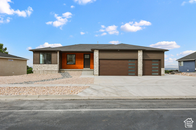 View of front of house with a garage, stone siding, and concrete driveway