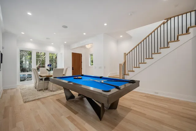a room with wooden floor pool table and windows