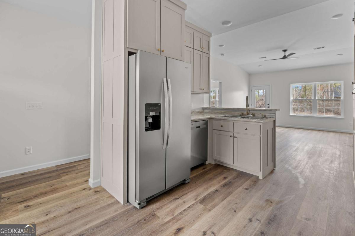 96 Beech Road Hazlehurst, GA 31539 - Photo 15 of 32 a kitchen with stainless steel appliances granite countertop a refrigerator a sink dishwasher and white cabinets with wooden floor