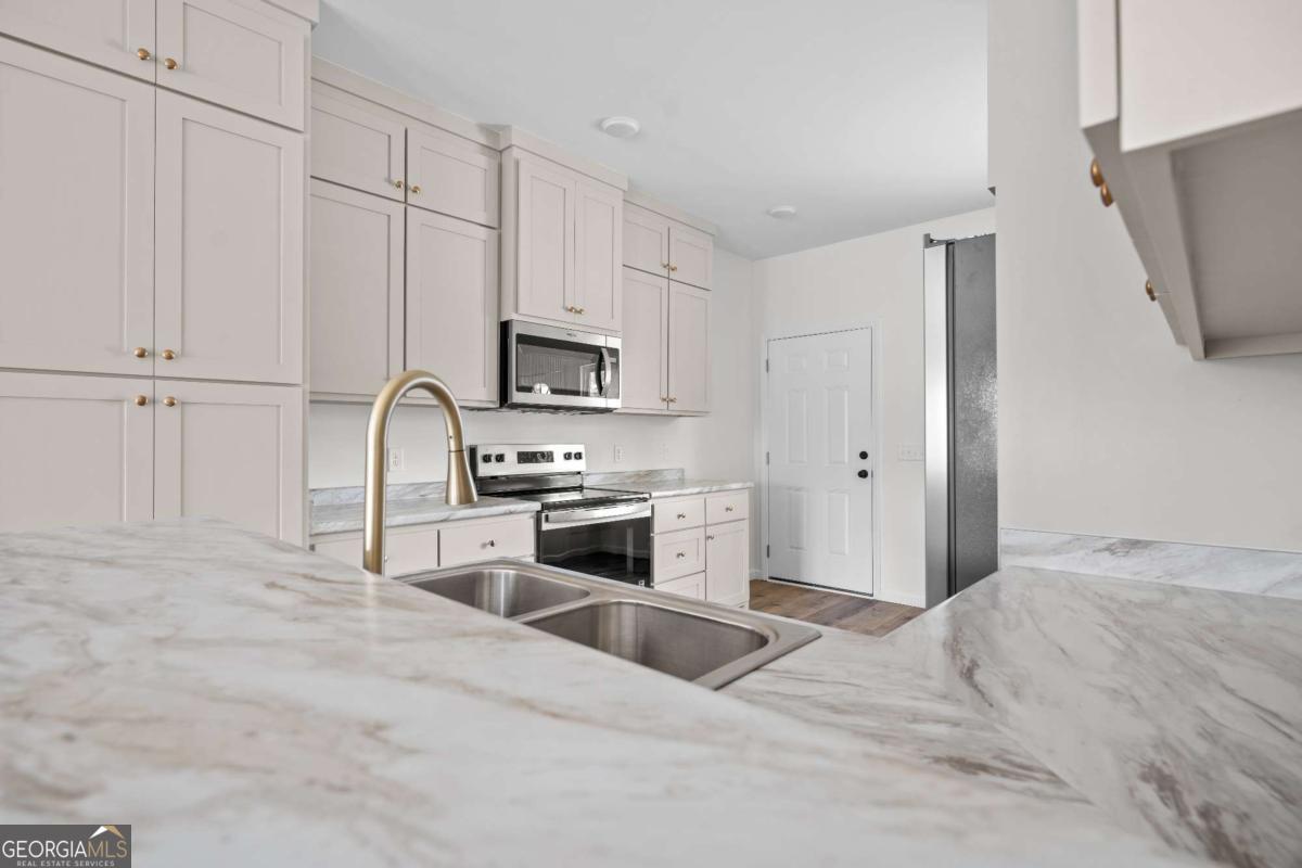 96 Beech Road Hazlehurst, GA 31539 - Photo 17 of 32 a kitchen with granite countertop a refrigerator stove and white cabinets