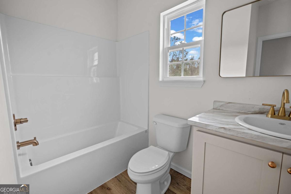 96 Beech Road Hazlehurst, GA 31539 - Photo 29 of 32 a bathroom with a granite countertop toilet a sink and a bathtub