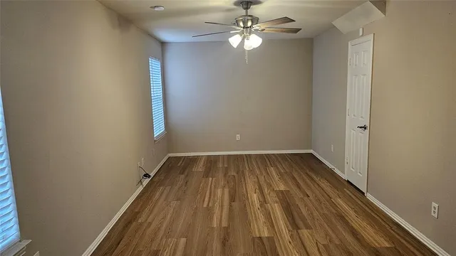 an empty room with a hardwood and ceiling fan