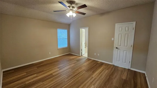 an empty room with wooden floor fan and windows