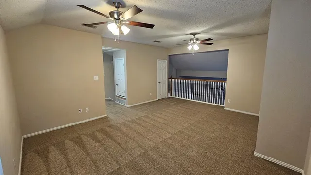 a view of an empty room with a ceiling fan and window