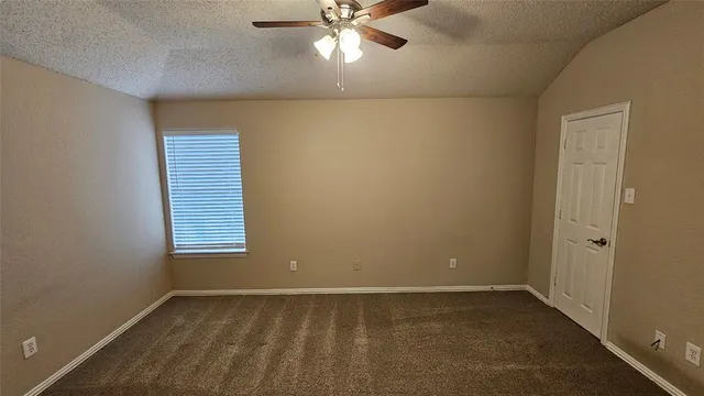 an empty room with a window and a chandelier fan