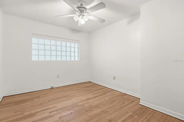 an empty room with wooden floor fan and windows