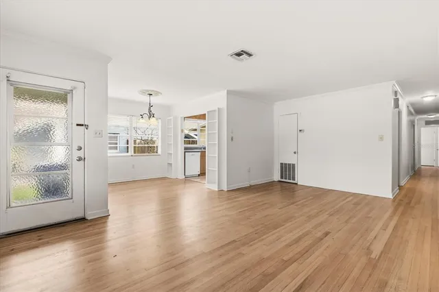 a view of an empty room with window and wooden floor