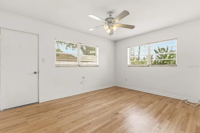 a view of an empty room with a window and wooden floor