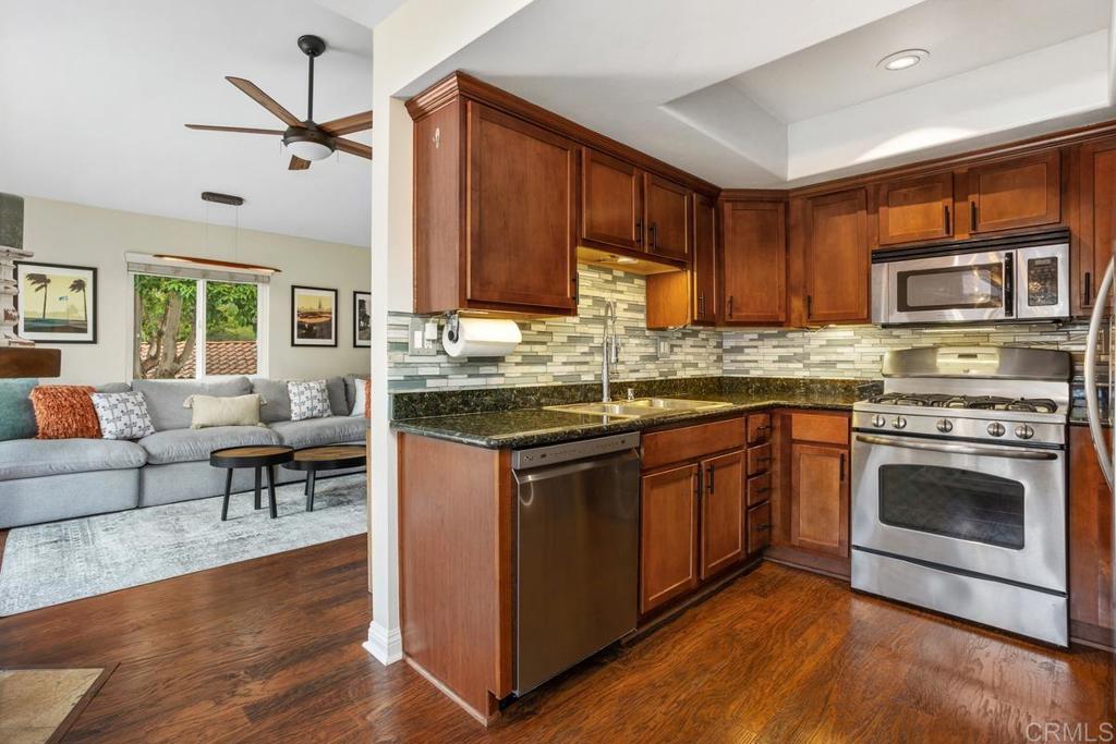 102 Sea Cliff Way Oceanside, CA 92056 - Photo 16 of 44 a kitchen with stainless steel appliances granite countertop a stove top oven a sink dishwasher a dining table and chairs with wooden floor