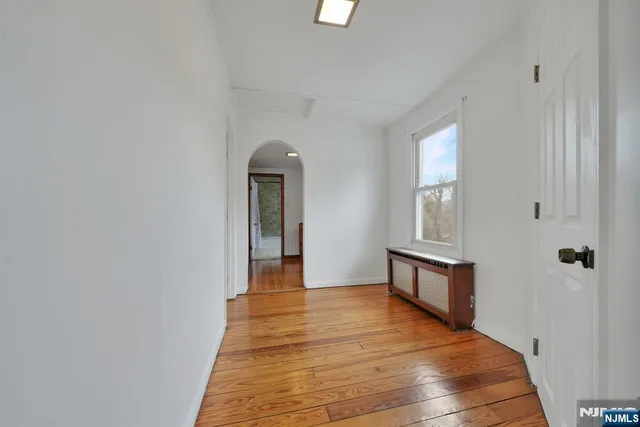 a view of a hallway with wooden floor and a living room