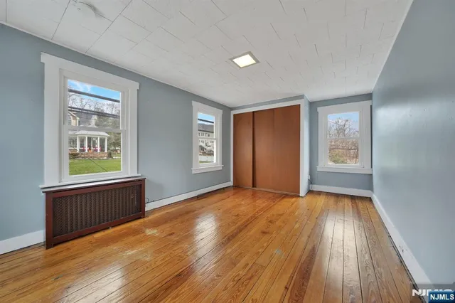 a view of an empty room with window and wooden floor