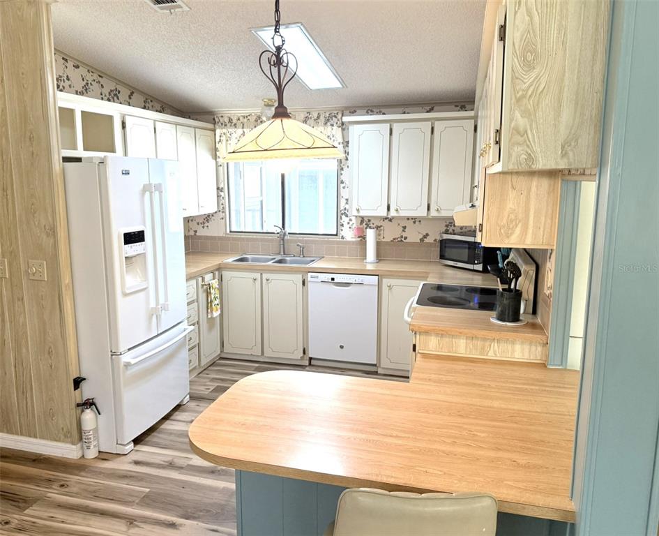 122 Rarotonga Road North Port, FL 34287 - Photo 11 of 48 a kitchen with stainless steel appliances granite countertop a refrigerator a sink dishwasher a stove with white cabinets and wooden floor