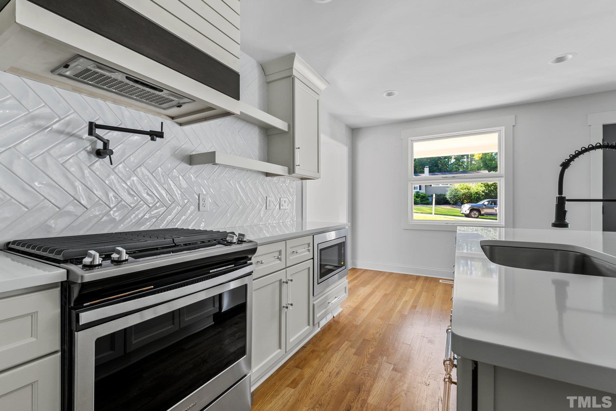 317 Quail Drive Raleigh, NC 27604 - Photo 16 of 29 a kitchen with a stove a sink and a microwave