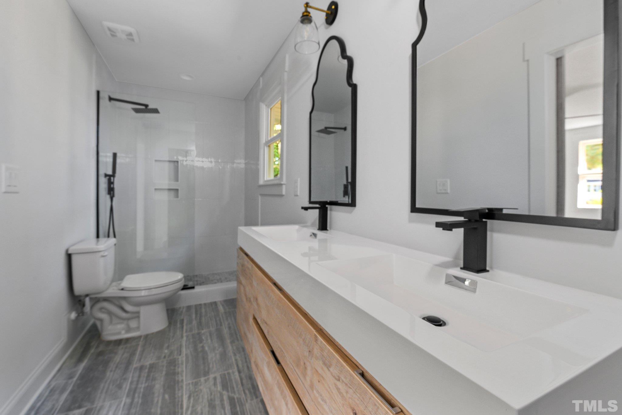 317 Quail Drive Raleigh, NC 27604 - Photo 8 of 29 a bathroom with a double vanity sink toilet and a mirror