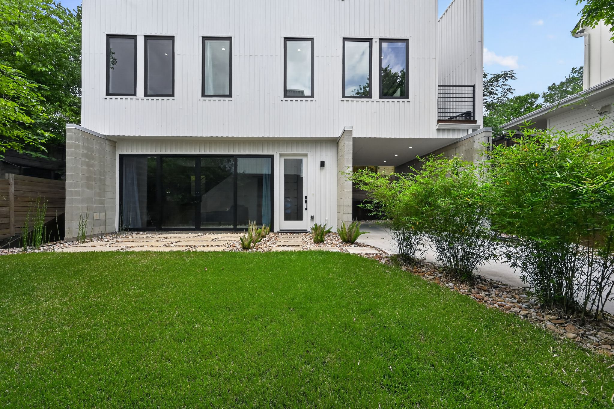 1206 Luna Street, Unit 2 Austin, TX 78721 - Photo 3 of 30 The property features a modern white facade with dark-framed windows, a well-maintained lawn, and a paved walkway leading to the entrance