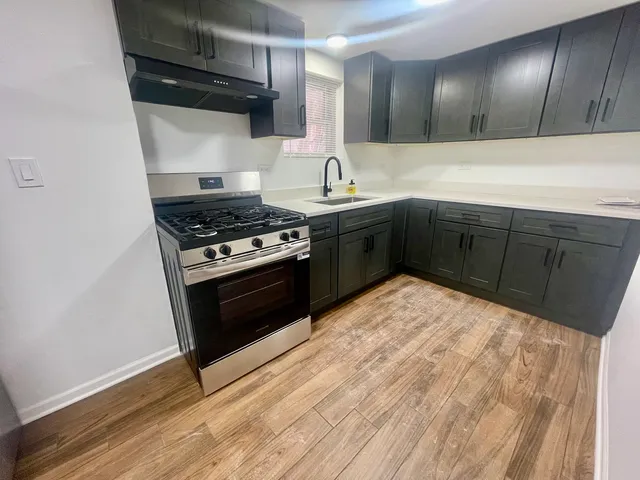 a view of kitchen with refrigerator stove and wooden floor