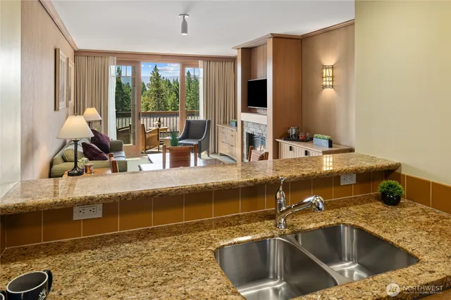 a kitchen with a sink and a large mirror next to a window