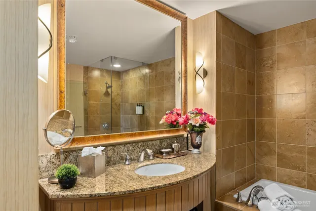 a bathroom with a granite countertop sink a large mirror and a shower