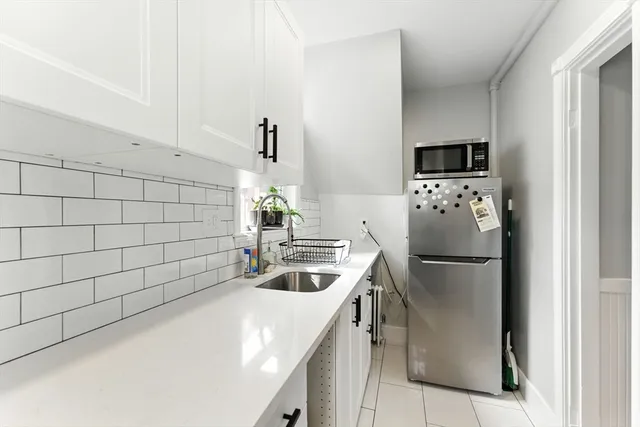 a kitchen with stainless steel appliances a refrigerator a sink a stove and white cabinets