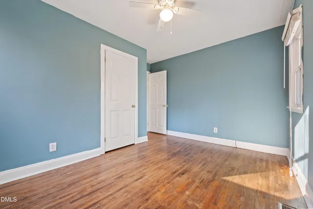 an empty room with wooden floor and fan