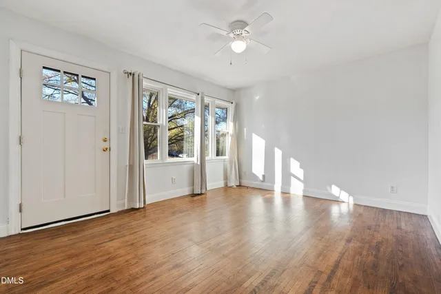 a view of an empty room with a window and wooden floor